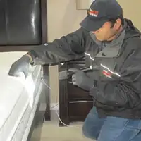 Bed bug inspection technician checking a mattress and bed frame for signs of infestation in Newark, NJ