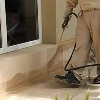 General pest control technician spraying exterior perimeter around a home in Newark, NJ