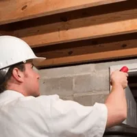 Termite inspection technician checking a basement wall and framing for termite activity in Newark, NJ