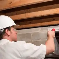 Termite inspection technician checking a basement wall and framing for termite activity in Newark, NJ